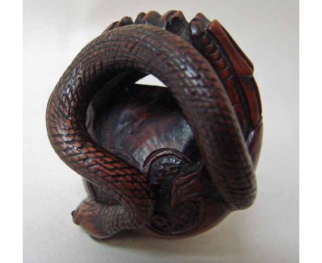 A Japanese carved wood netsuke as a serpent emerging from a pair of stylised dragons with a pearl, 4.2cm long 
