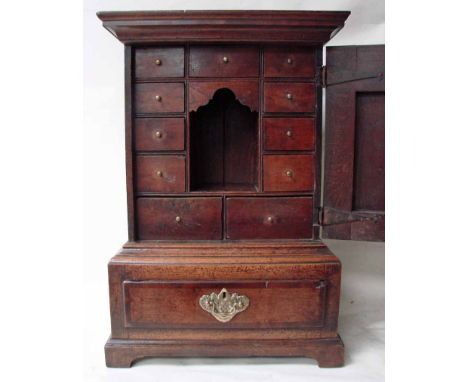 An eighteenth century oak and crossbanded table top cabinet, ogee moulded cornice above a hinged door with crossbanded wavy t