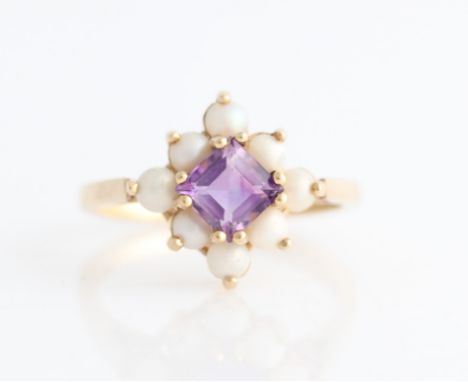 A hallmarked 9ct yellow gold amethyst and split pearl ring, set with a central square cut amethyst surrounded by a border of 