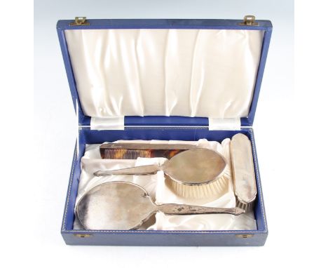 A boxed silver mounted dressing table set, comprising a hair brush, a hand brush, a mirror, and a comb of faux-tortoiseshell,