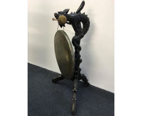 A large floor standing brass dinner gong in tree trunk form with dragon wrapped around base, on tri-form base.