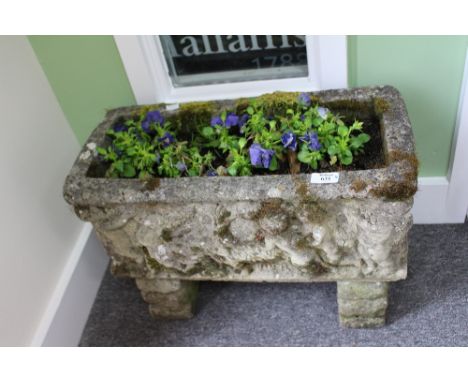 A RECONSTITUTED STONE TROUGH decorated with cherubs, 55cm wide x 26cm deep x 39cm high