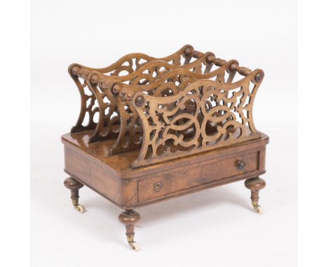 A VICTORIAN WALNUT CANTERBURY  with fretwork decorated divisions, a single drawer and turned legs standing on ceramic castors