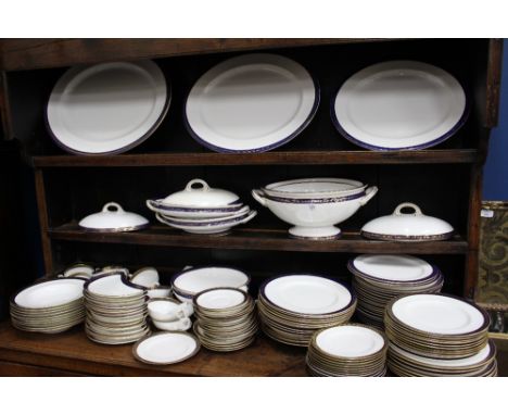 A ROYAL WORCESTER PORCELAIN DINNER SERVICE with a cobalt blue and gilded greek key border, to include three platters, four tu