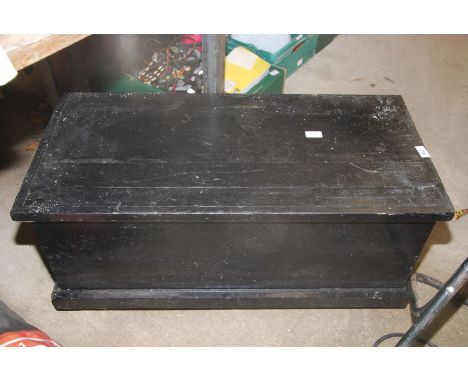 A black painted wooden trunk on castors, 34'' wide x 16'' deep x 15 1/2'' high.
