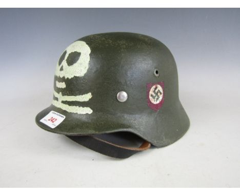 A restored WWII German steel helmet with decals and painted skull and cross bones device