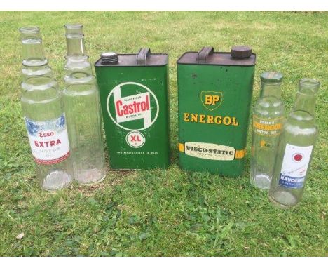 Four glass oil bottles, a Castrol gallon can and a BP gallon can. 