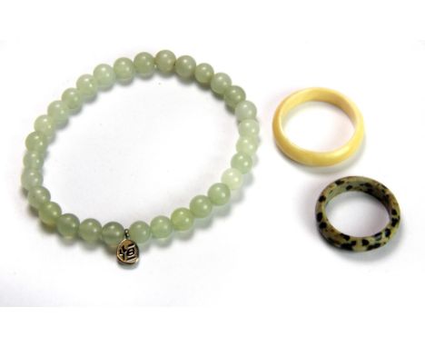 A jade bracelet, a speckled stone ring and an ivory ring.