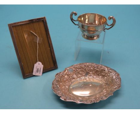 A silver two-handled cup, Birmingham 1905, an oval, embossed silver dish, Chester 1899, approx. 13oz. and an engine-turned si