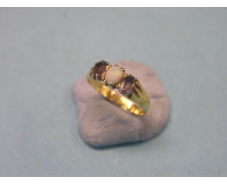 A yellow metal ring, claw-set with central opal and two amethysts, size K/L