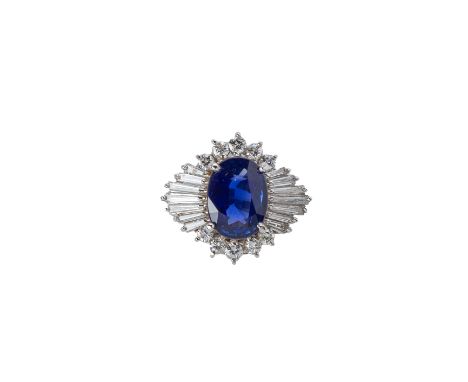 A BLUE SAPPHIRE AND DIAMOND RING
Set in platinum, the oval blue sapphire within a surround of tapered baguette and round bril