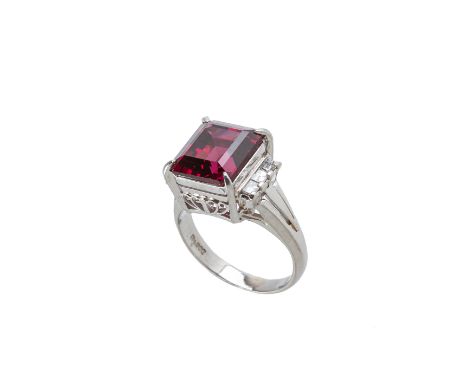 A GARNET AND DIAMOND RING
Set in platinum, the square step cut garnet flanked by three baguette cut diamonds within a foliate