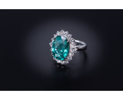 AN APATITE AND DIAMOND CLUSTER RING Set in platinum, the oval cut apatite within a surround of round brilliant cut diamonds  