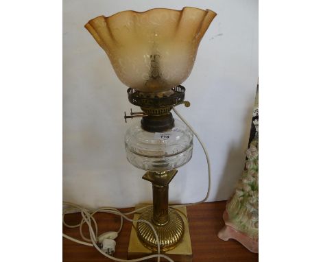 A late 19th/early 20th Century oil lamp with frilled glass shade, clear glass font and brass column base with later electrica