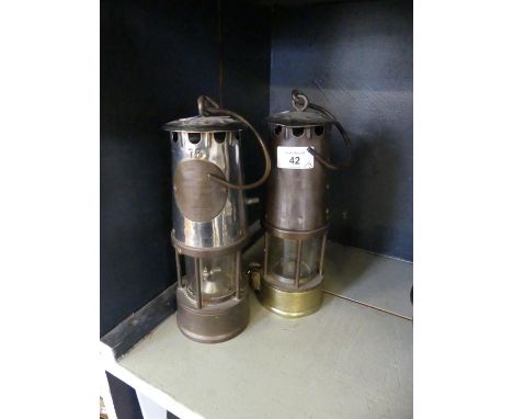 Two vintage miners lamps both marked The Protector lamp and Lighting co Eccles 