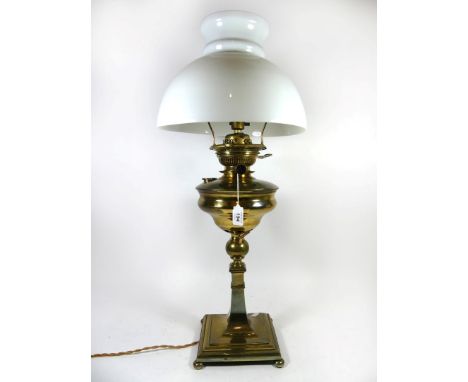An early 20th Century brass oil lamp converted to electricity, having circular oil reservoir raised on single block support a