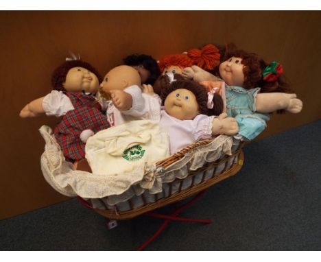 Cabbage Patch Dolls - A Moses basket with stand containing 7 dressed Cabbage Patch Dolls, a small collection of extra clothin