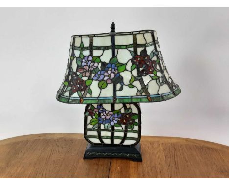 IN THE MANNER OF TIFFANY, LEADED GLASS TABLE LAMP the shade decorated with foliage, over a similarly decorated oblong body an