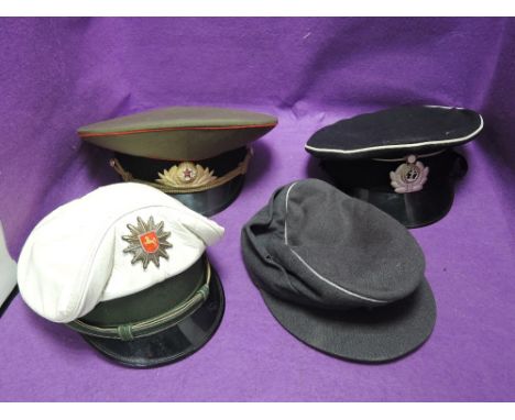 A collection of four military caps, World War II German, 1982 German, Russian Navy, and Russian Army