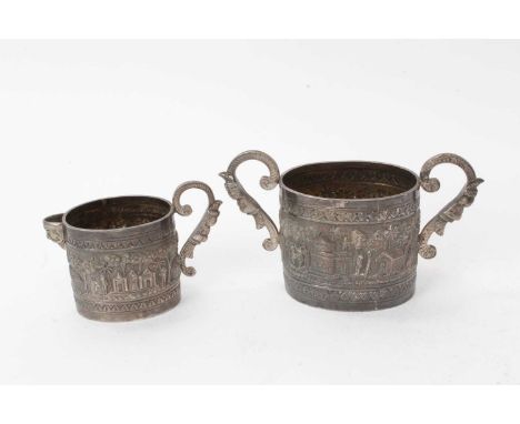 Indian white metal sugar basin and milk jug of oval form, with chased and engraved decoration of rural scenes (apparently unm