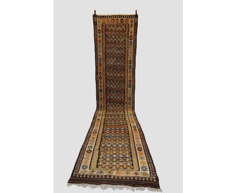 Senneh ghileem runner, north west Persia, circa 1930s; 16ft. 4in. X 3ft. 6in. 4.97m. X 1.07m. Dark brown field with all over 