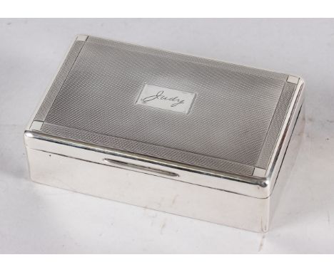 A rectangular engine turned silver table cigarette box, lid engraved "Judy" 