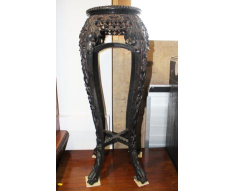 A Chinese hardwood torchere with marble and mother-of-pearl top and pierced and floral carved decoration, on quadruple splay 
