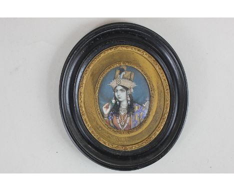 An Indian miniature portrait of a lady, finely dressed, holding a rose, with gilt embellishments, 6cm by 4.5cm