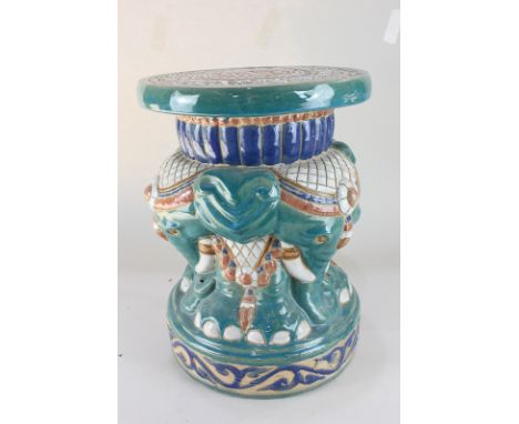 A glazed pottery stool decorated with elephants, in red, blue and green, circular top 28cm
