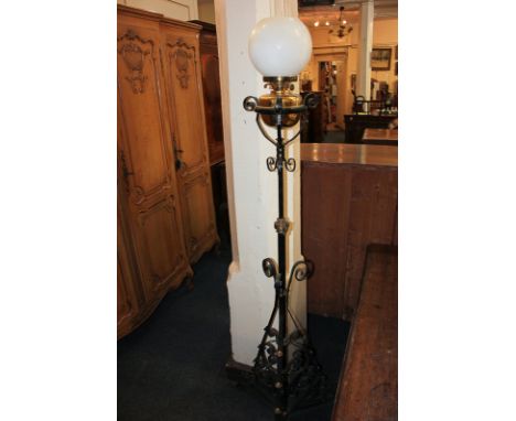 A Victorian cast iron oil standard lamp with white glass globular shade, on adjustable scrolling stem and tripod legs