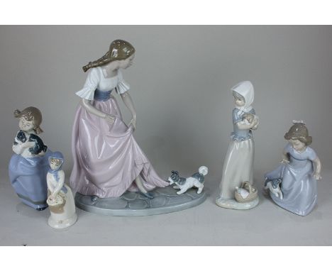 A large Nao figure of a woman with a puppy pulling on her dress together with three smaller Nao figures of girls with puppies