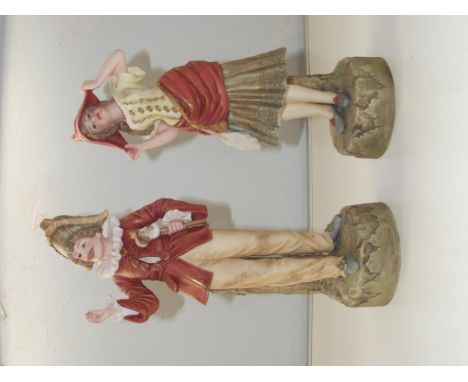 A pair of Robinson and Leadbetter Parian ware figures of a gentleman holding a stick with a jesters head and a lady holding h