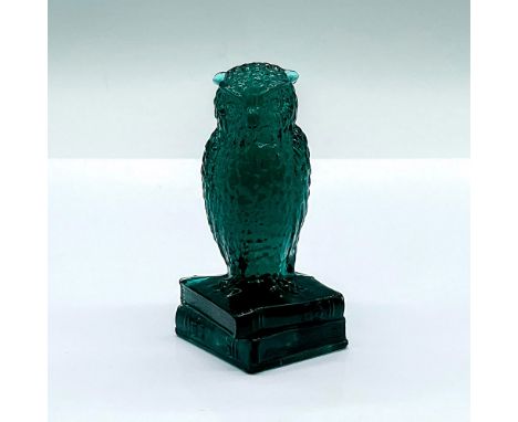 A dark green glass figure of an owl perched on a stack of books. Degenhart mark on the base. Figure gives a fluorescence glow
