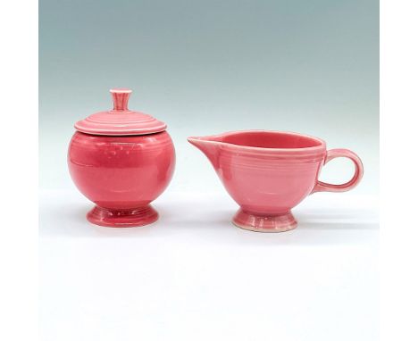 A ceramic pink tableware set consisting a covered sugar bowl and a creamer. HLC Fiesta marked on the bases. Bowl: 3.5"W x 4.5