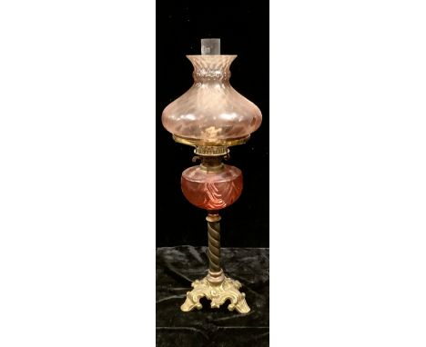 A late 19th century oil lamp, cranberry glass reservoir, pink tinged shade, Duplex twin burner, barley twist column, brass ba