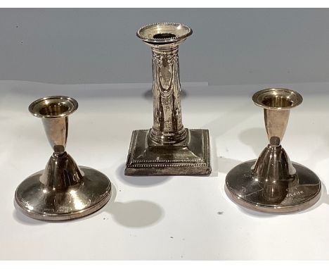 A pair of silver boudoir candlesticks, Birmingham 1957, 8.5cm high; another candlestick, Sheffield 1908, 12cm high (3) 