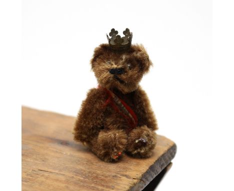 Toys &amp; Juvenalia - a mid 20th century miniature jointed brown mohair teddy bear, pin eyes, wearing a red and white sash a