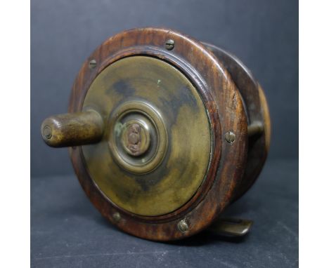 A vintage hardwood and brass freshwater fishing reel with full line, Diameter 12cm 