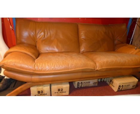 A retro three seater sofa upholstered in tan leather raised on aluminium supports