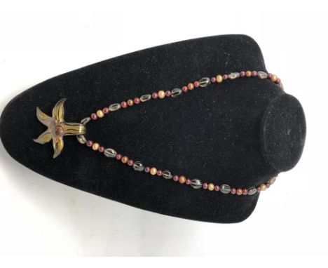 A cultured freshwater pearl and topaz beaded necklace with starfish pendant and silver clasp.