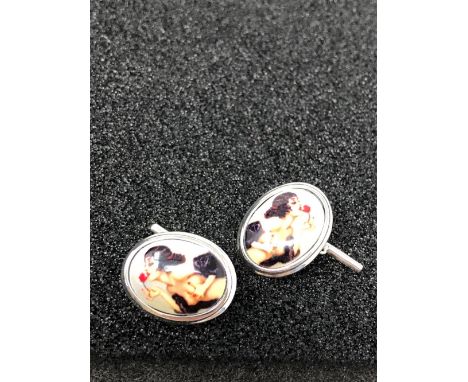 A pair of silver and enamel cufflinks depicting a semi nude lady.