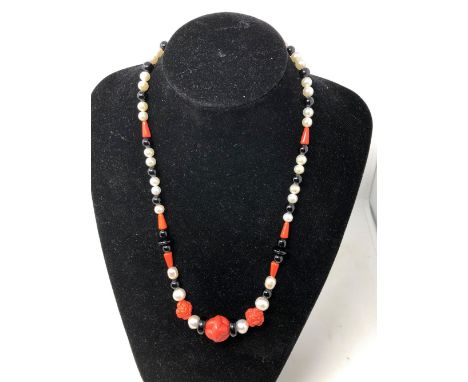 A freshwater pearl, onyx and coral necklace.