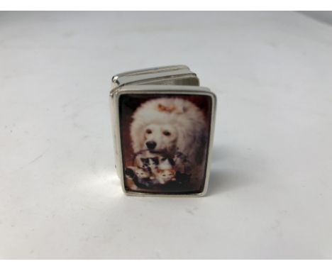 A silver pill box with enamel lid depicting a French poodle carrying a basket of kittens.