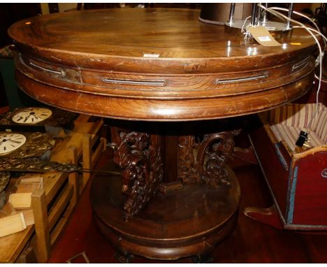 An early 20th century Chinese elm circular centre table, the column issuing floral scroll relief carved panelled decoration, 