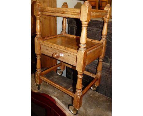 A rustic pine two-tier whatnot, having single long central drawer raised on roller castors, width 47cm
