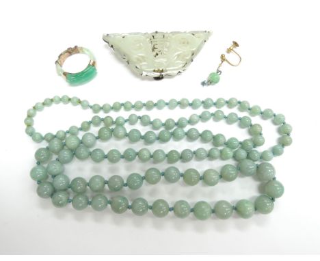 A graduated jade bead necklace, carved jade dress clip and a carved jade ring (broken)
