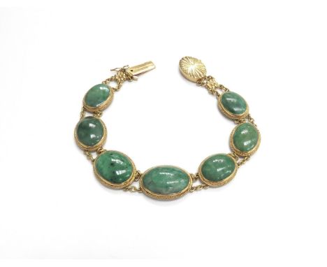 A gold bracelet with seven oval jade panels, stamped 18k, 19cm long, 21.8g total