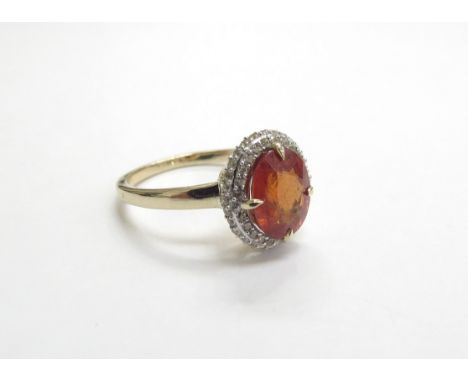 A 9ct gold dress ring with central oval orange stone possibly fire opal framed by white stones. Size O, 2.8g