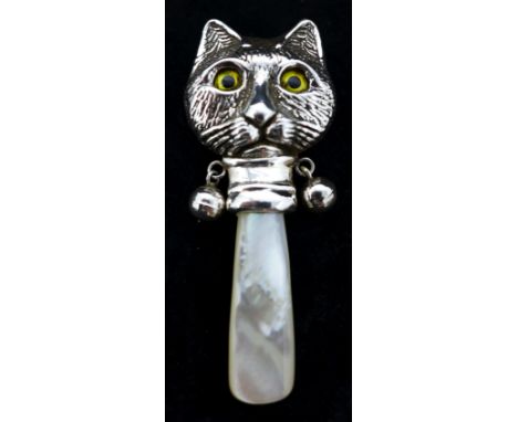 A sterling silver baby rattle in the form of a cat's head with glass eyes and a mother of pearl handle 