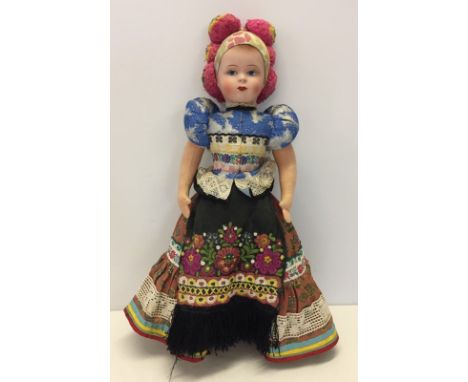A fully jointed fabric bodied vintage doll in traditional dress. Approx 56cm long. 